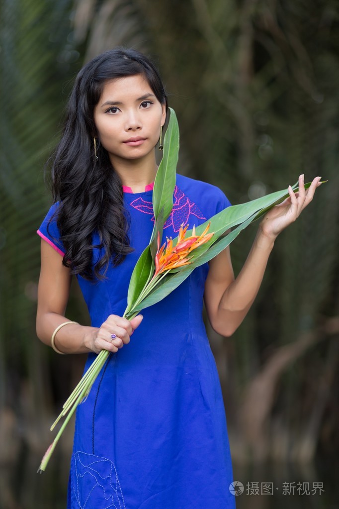年轻女子手捧鲜花的蓝色 ao dai