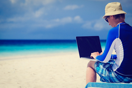 笔记本电脑在海滩度假的人