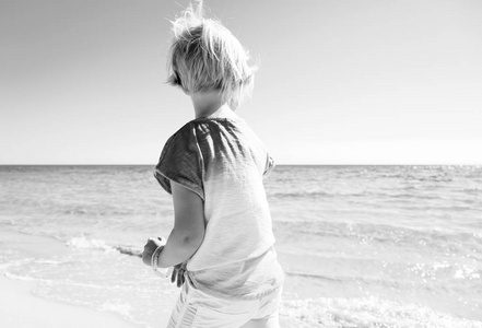 从后面看到的现代女孩在彩色衬衫上海滨漫步