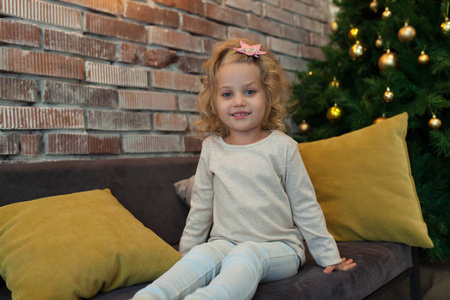 一个可爱的小女孩, 穿着灰色的白色汗衫, 在圣诞树附近。模拟