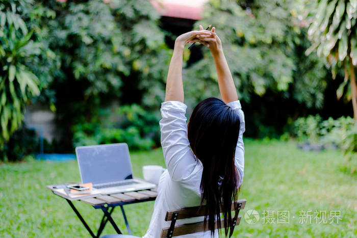 年轻的企业妇女在户外咖啡馆工作时伸出双手