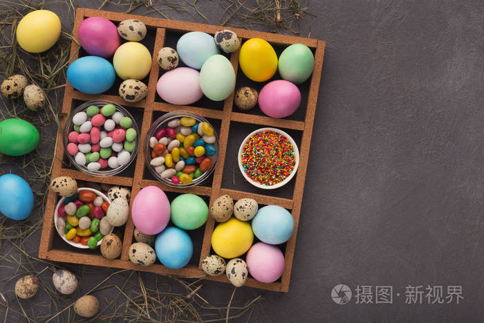 彩色复活节彩蛋和小糖果框架上的灰色背景
