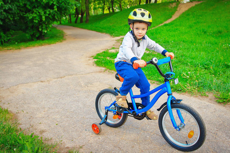 小男孩在绿色公园户外夏天上自行车