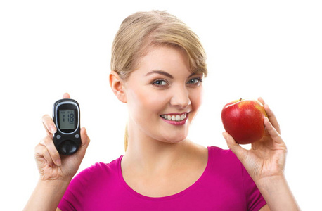 幸福的女人抱着血糖仪和新鲜苹果，测量和检查糖水平概念