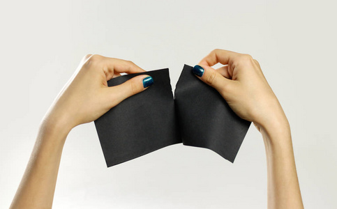 女手撕一张黑纸。孤立在灰色的背景和目标