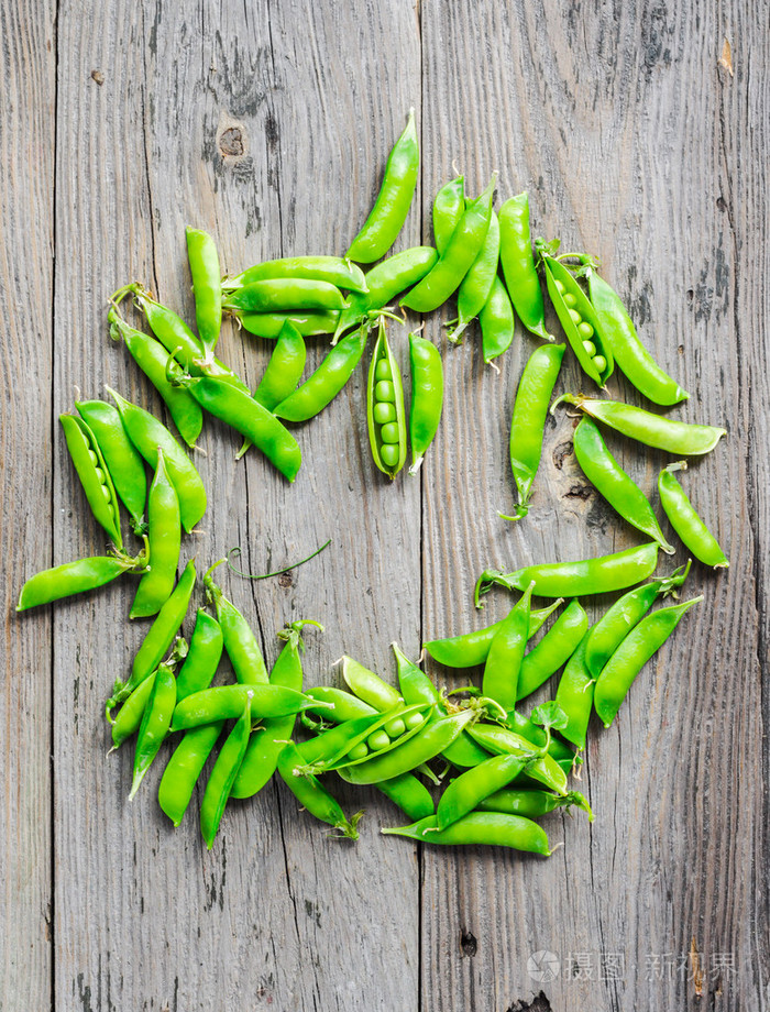 绿色豌豆在豆荚年轻的灰色木背景质朴roun