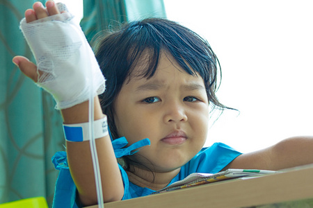 疾病亚洲孩子坐在椅子上在医院里，盐渍 intravenou