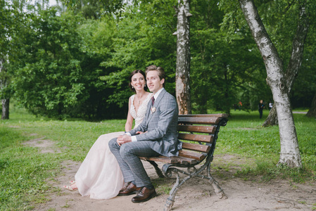 新娘和新郎坐在湖附近的一个公园的长椅上