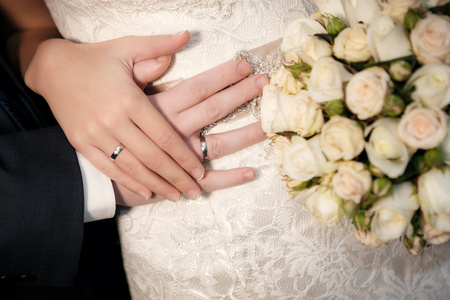 新郎和新娘结婚戒指与从玫瑰婚礼花束手
