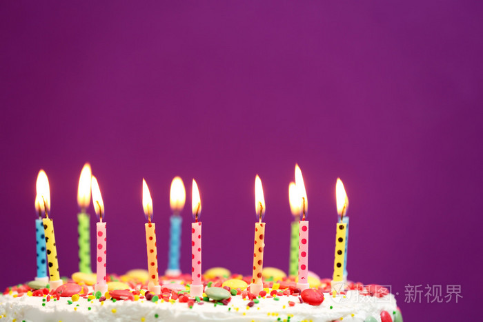 与紫色背景上的蜡烛的生日蛋糕