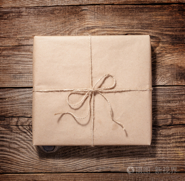 旧木板上棕色纸板的邮包. 绳子