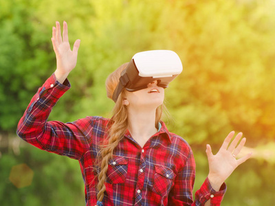 在自然背景下的虚拟现实头盔的女孩。举起手来