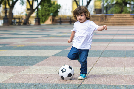 孩子们混凝土在混凝土表面上踢球的孩子照片