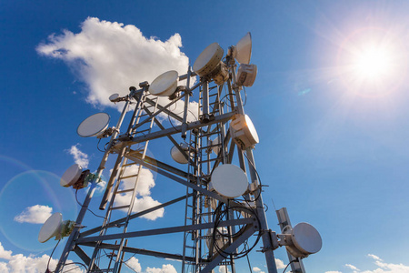 电信塔与电视天线卫星盘微波和小组天线移动操作员对蓝天和太阳