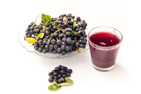 鲜榨果汁的玻璃和 beries 在锅中，孤立的白色背景上的黑色苦莓 黑 melanocarpa