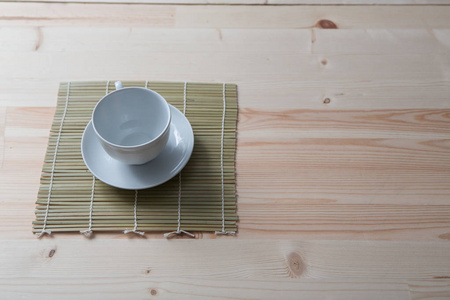 一个纯白色的陶瓷茶杯和茶碟站在一张小木桌