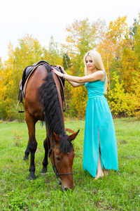女孩与一匹马走在一个秋天的树林