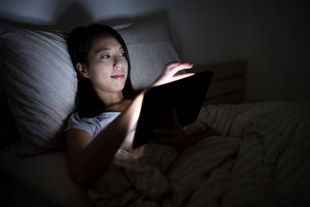 女人在晚上使用平板电脑