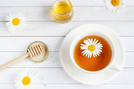 一杯甘菊茶和蜂蜜白色木制背景上