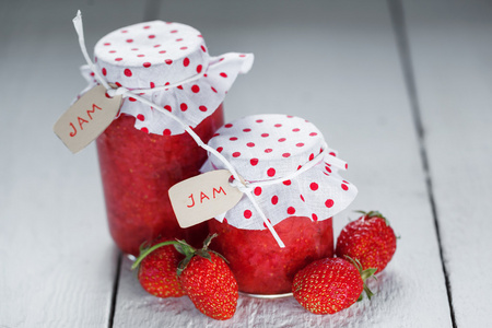 新鲜草莓自制果酱在白色背景上的罐子里。健康有机食品和素食食品