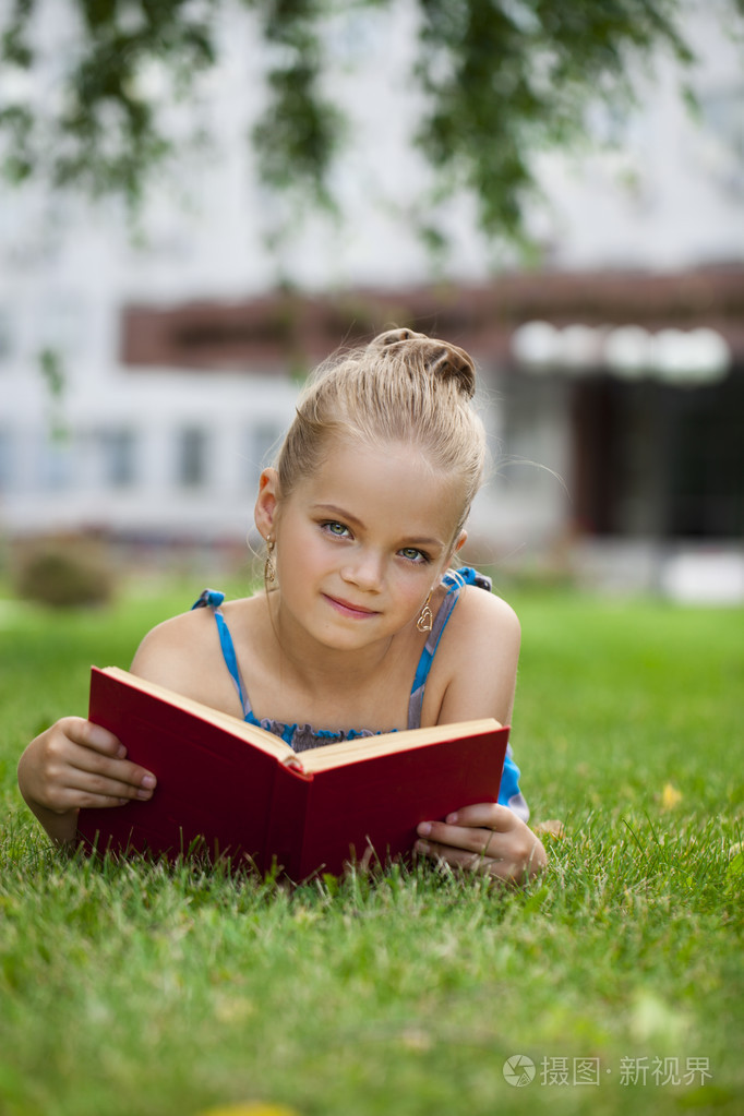 外面的草地上读书的可爱可爱的小女孩