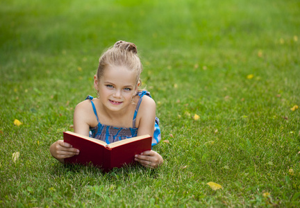 外面的草地上读书的可爱可爱的小女孩