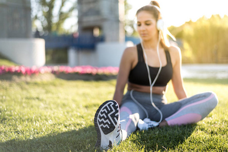 体育锻炼草坪和伸展在公园听音乐户外草地上的女人