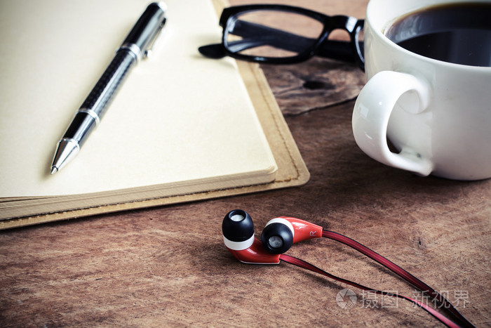 与咖啡和笔记本上旧木桌子耳机的特写