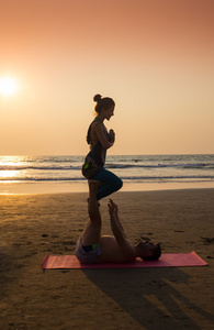 年轻夫妇坐在海滩瑜伽练习