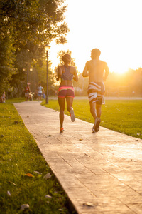 年轻的夫妇在日落时分在公园跑步
