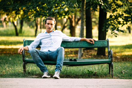 英俊的成年男子坐在长凳上