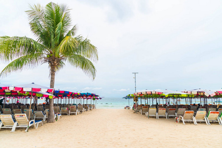 棕榈伞与坐在椅子上海滩