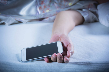 用手机在卧室里的床上睡觉的女人她闭着眼睛休息照片