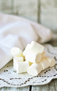 与旧的木制背景白色老式餐巾纸上的白色棉花糖照片