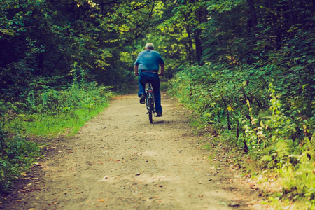 男子骑着自行车穿过夏季森林的旧照片