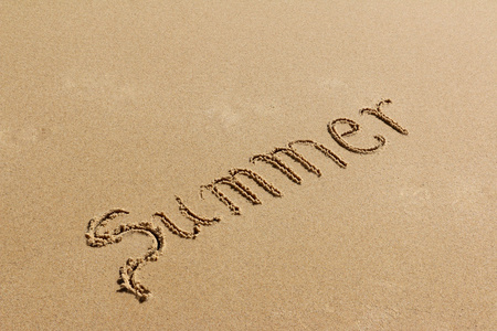 夏天的手在海滩上的沙子上的文字