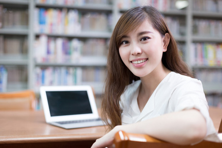 亚洲女学生在图书馆中使用笔记本电脑