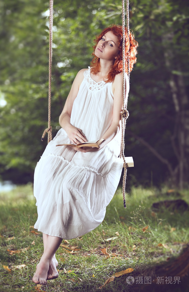 在秋千上的漂亮的红头发女人