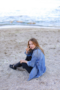美丽的姑娘休息，坐在海边，并构成 b 上的相机上