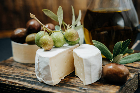 暗绿色的橄榄 油 山羊奶酪在木板上