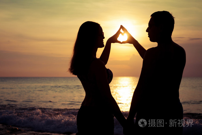 夫妻爱背光源剪影在海上日落的时候