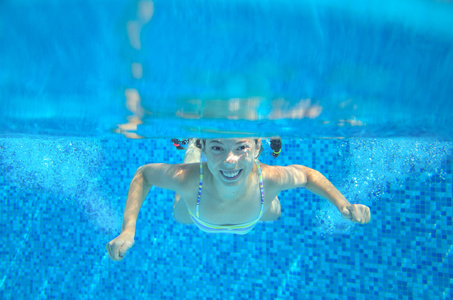 快乐儿童游泳在游泳池水下，好动的小孩游泳 踢球和乐趣，儿童水运动