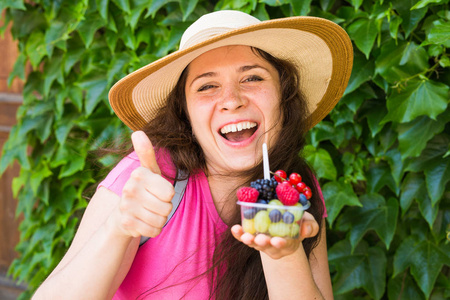 生态食品和健康的生活方式概念肖像微笑的女人抱着浆果和显示大拇指手势
