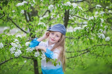 一个美丽的小女孩在春天开花花园的肖像。金发的盛开的花园里可爱的孩子