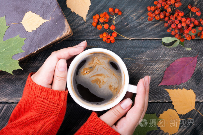 女人手里拿着杯咖啡秋木背景上.