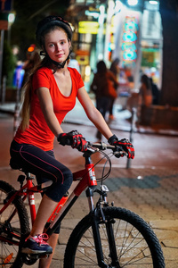城市夜骑自行车。女孩子们穿着自行车头盔