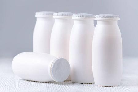 在灰色的背景上的塑料瓶里喝酸奶照片