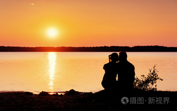 浪漫的情侣在七彩的晚霞在海滩上背景