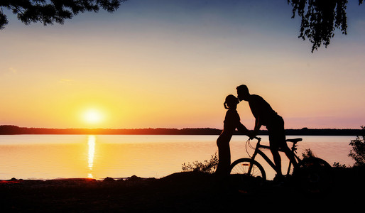 夫妇在一辆自行车在日落时分在湖边