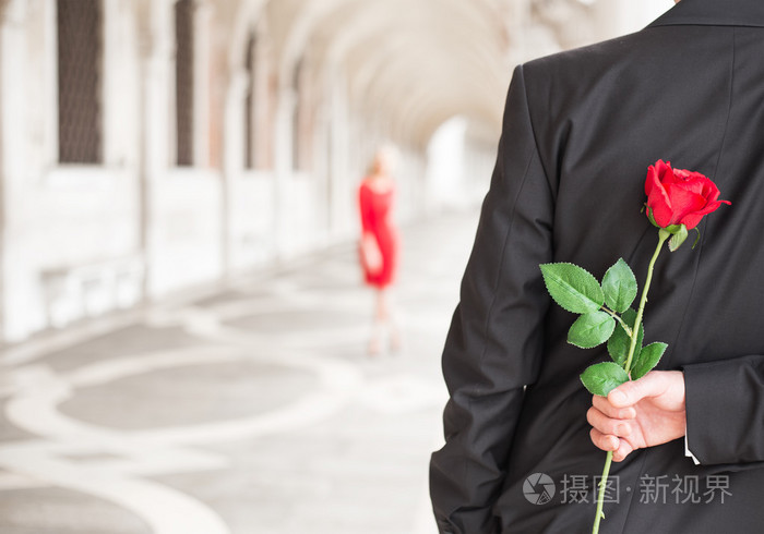 男人背着红玫瑰等着他的约会
